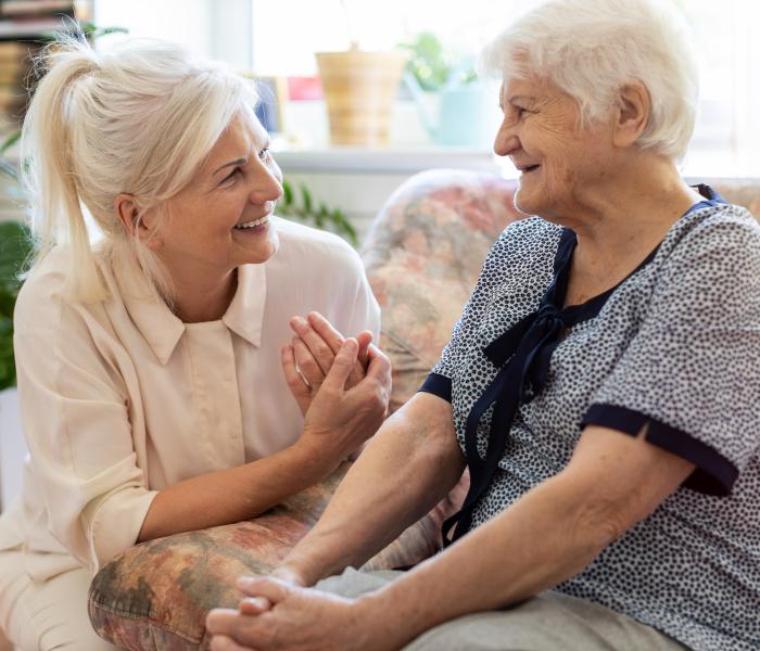 Oudere dame met haar thuishulp, lachend in gesprek