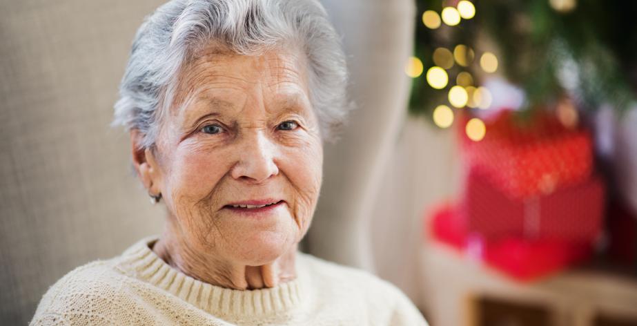 Senior alleen thuis met kerstboom